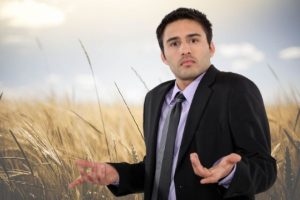 Человек разводит руками на фоне пшеницы